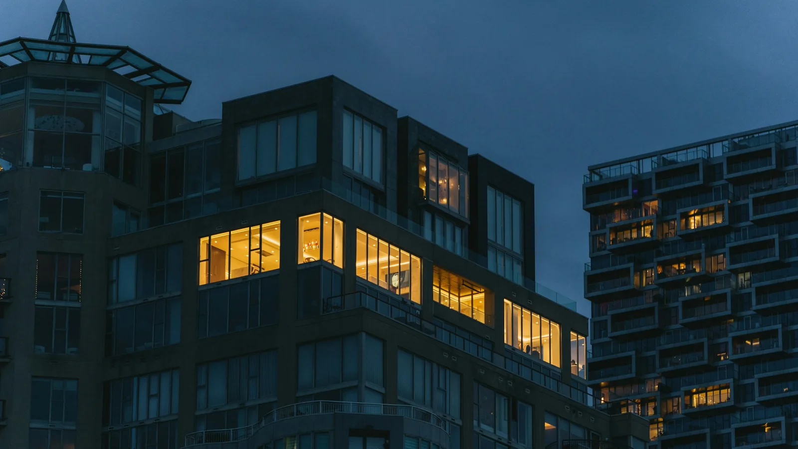 Condo towers at dusk with lights on in the units