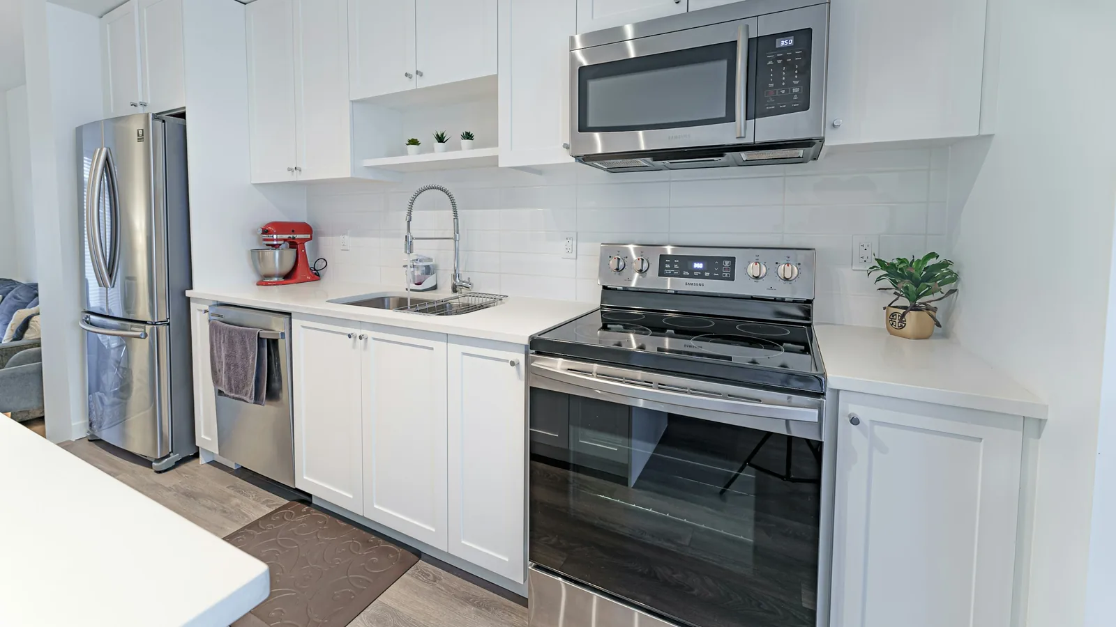 A kitchen with white cabinets and stainless steel appliances, condo towers