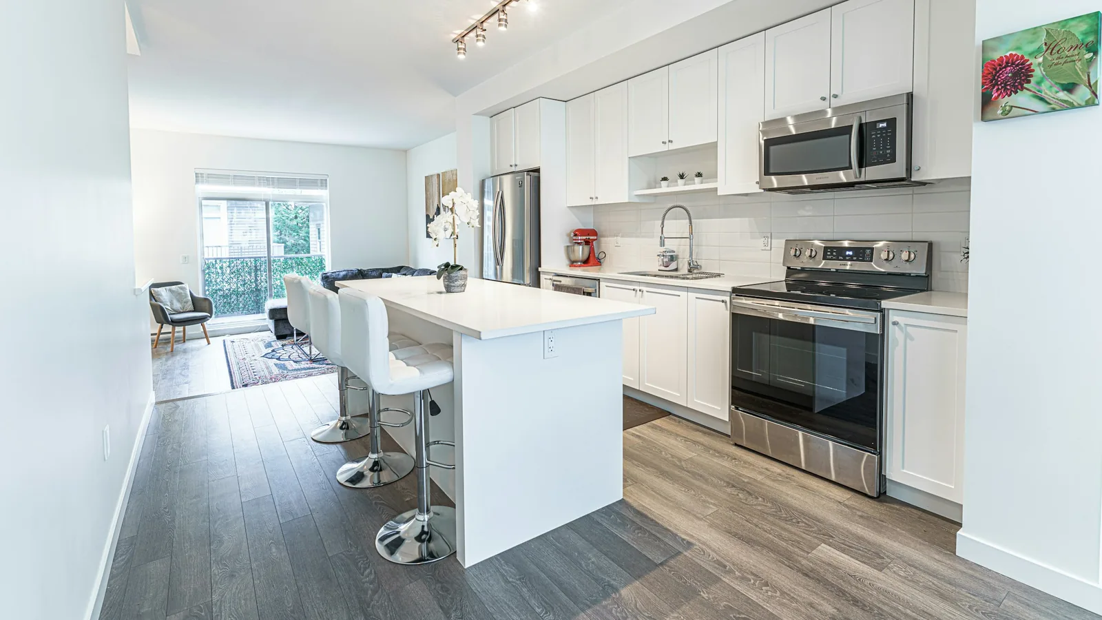 A kitchen with white cabinets and stainless steel appliances, condo towers