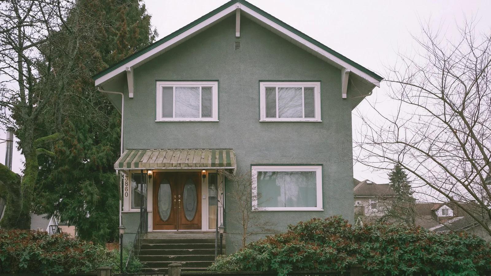 A green house with a brown door and a brown fence, Vancouver