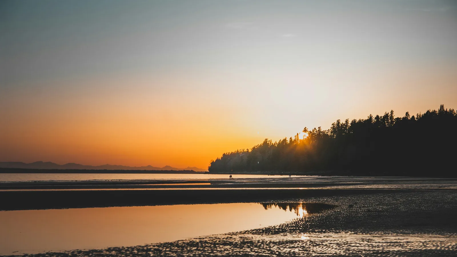 The sun is setting over the water at the beach, the White Rock waterfront