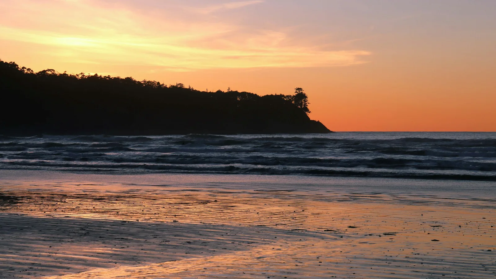 Pacific Northwest beach at sunset with forested headland