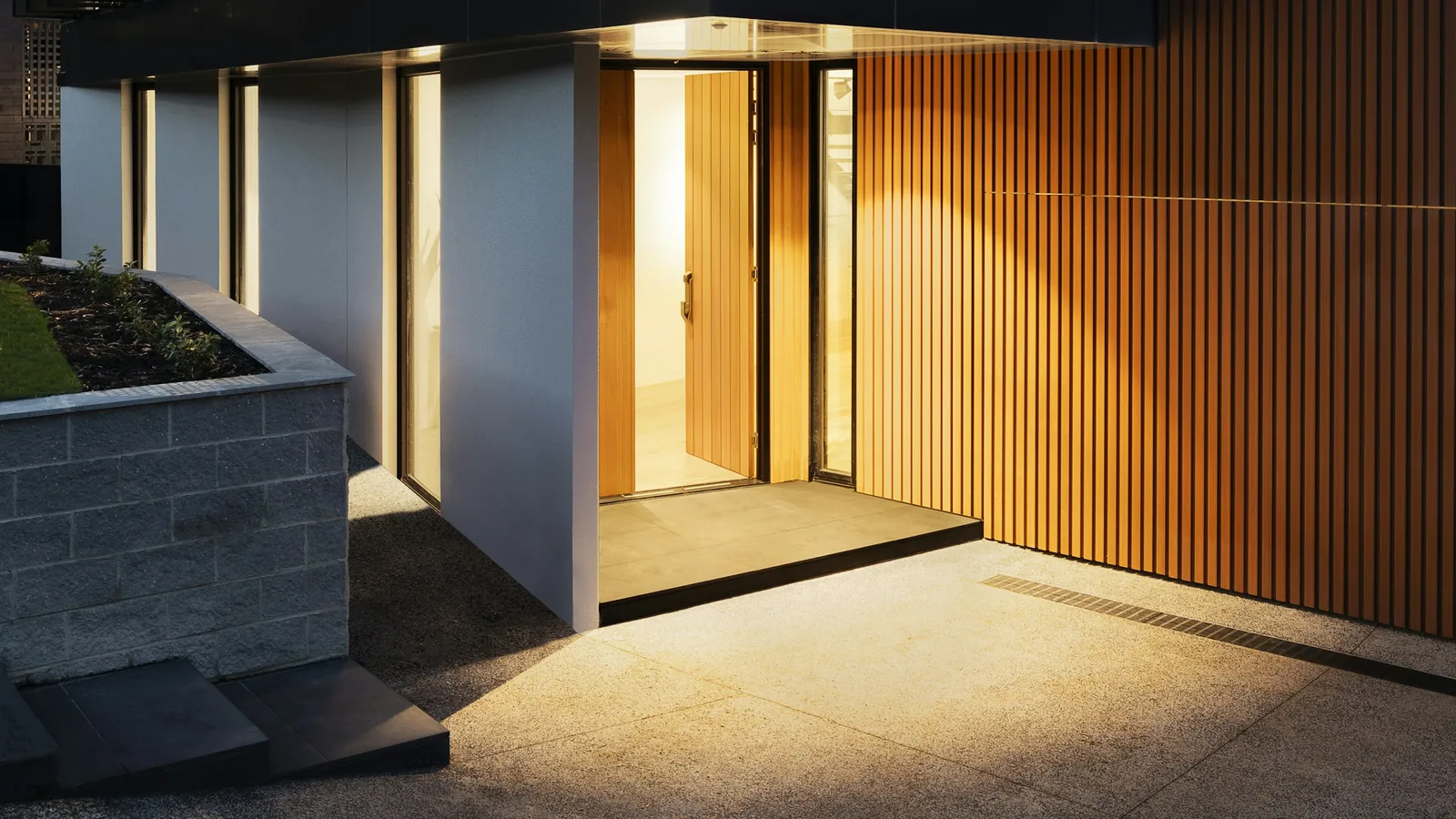 Entrance of a modern home with warm timber cladding at dusk