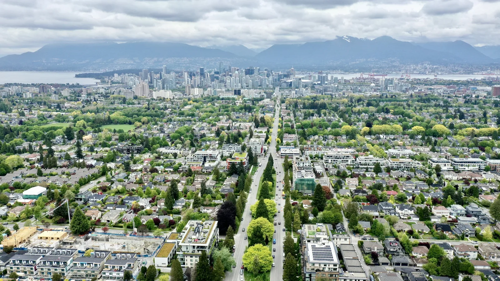 Aerial view over Kitsilano rooftops towards downtown Vancouver and the mountains