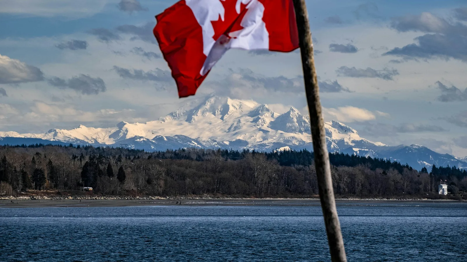 A canadian flag flying over a body of water, the White Rock waterfront