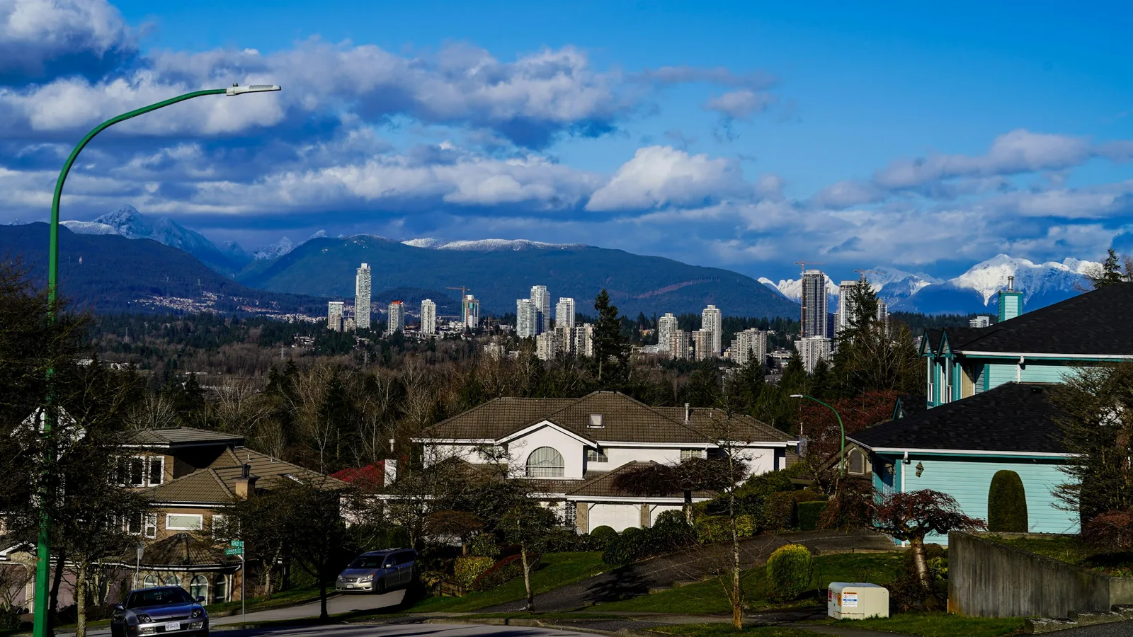 Burnaby skyline rising behind a residential neighbourhood with mountains beyond