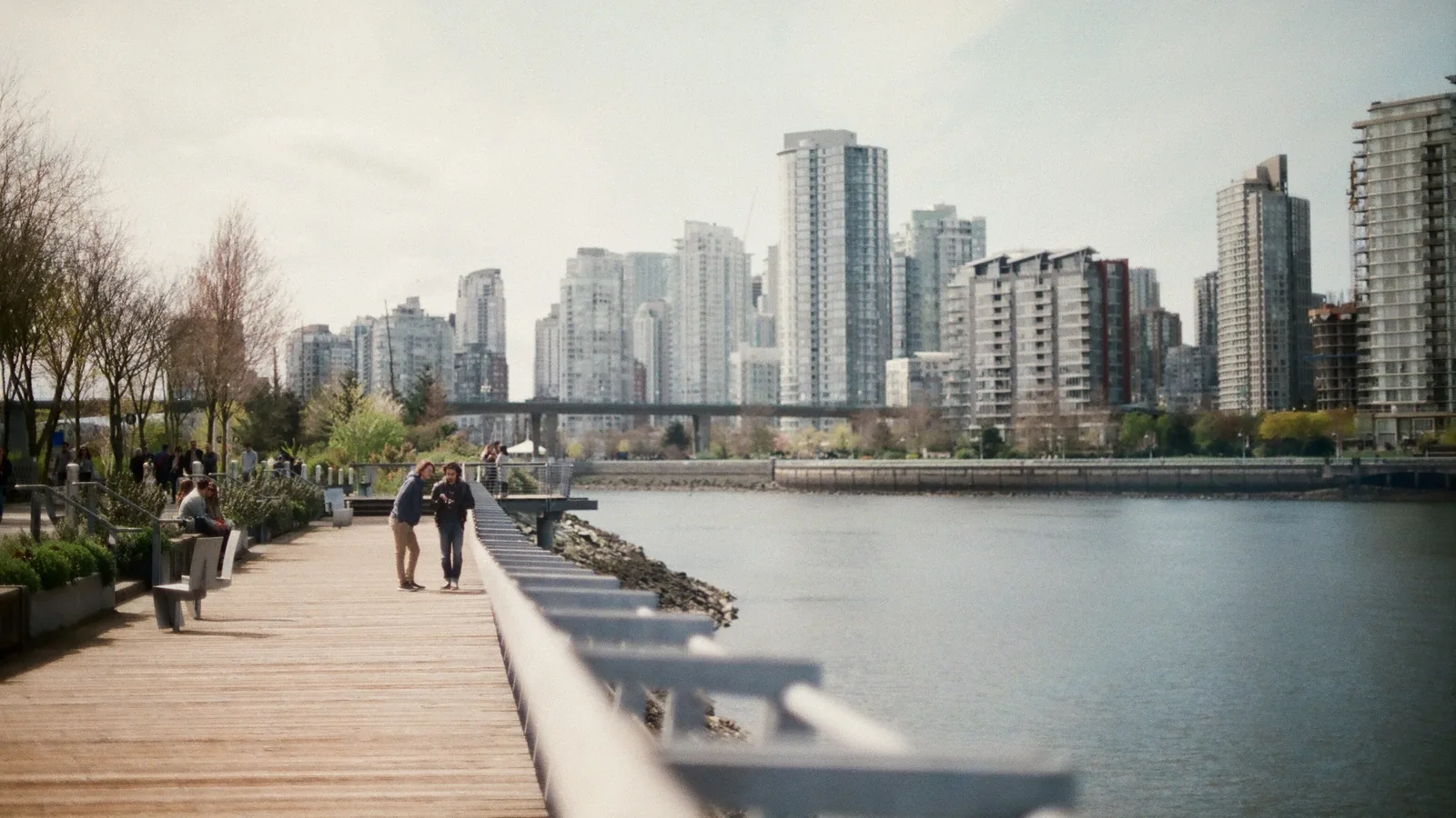 Two women walking on brown dock near body of water in Vancouver