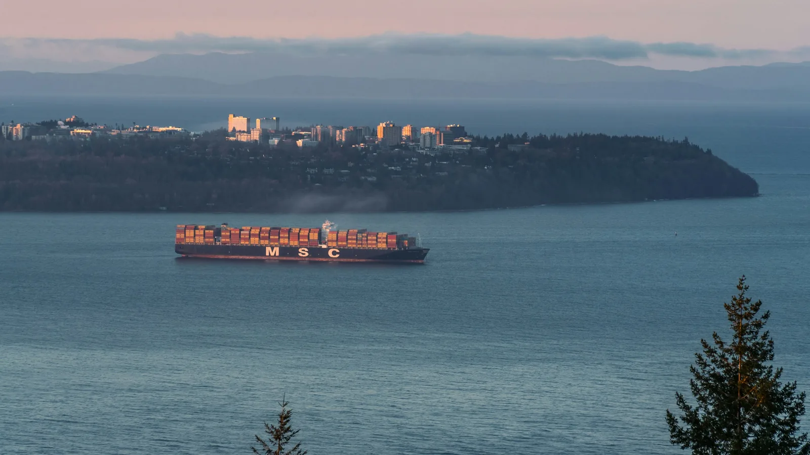 A large cargo ship sailing across a large body of water, the BC coast