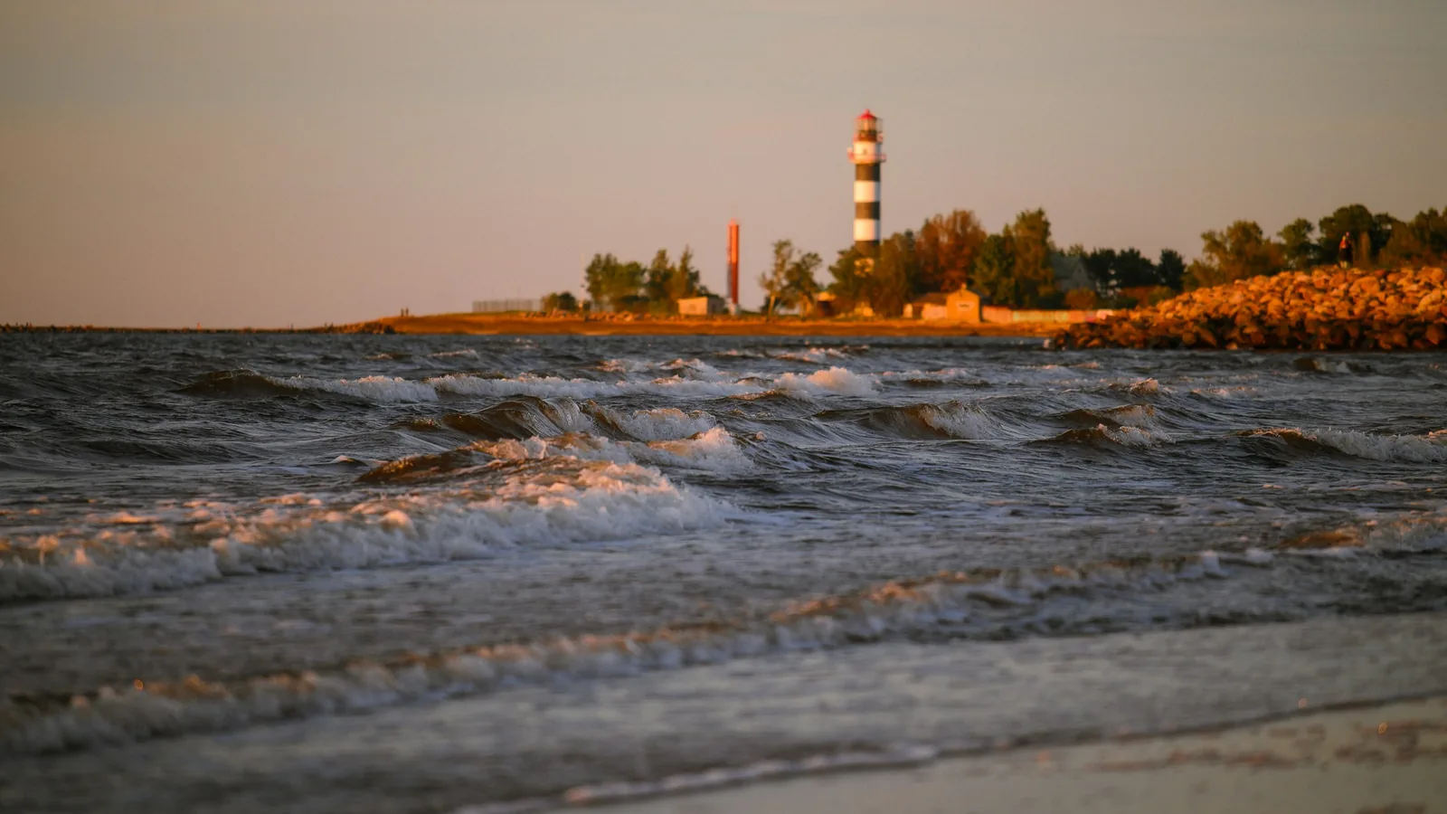 Waves breaking near a lighthouse at sunset